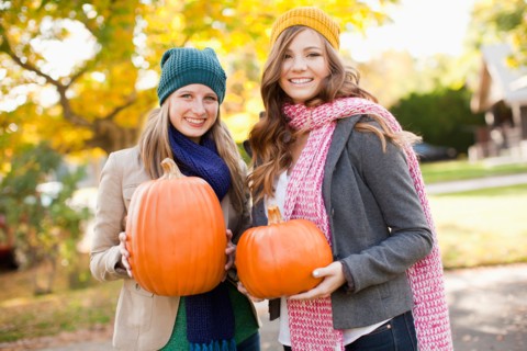 Portrait of two young women holding pumpkins. Photo: Jessica Peterson