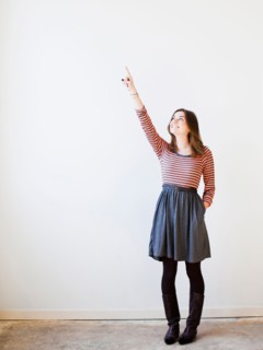 Studio shot young woman looking up and pointing. Photo : Jessica Peterson