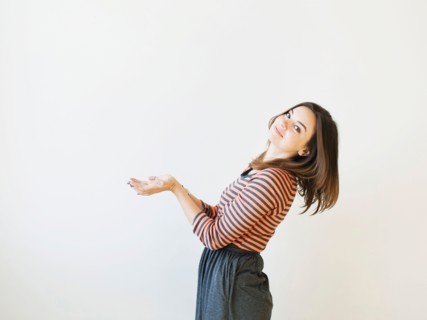 Studio shot young woman bending over backwards pretending like holding something. Photo : Jessica
