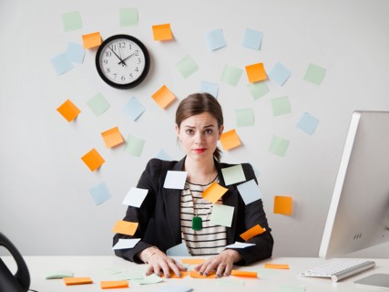 Studio shot of young woman working in office covered with adhesive notes. Photo: Jessica Peterson