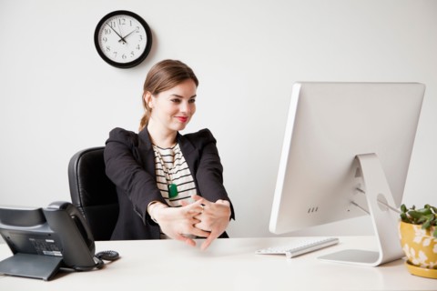 Studio shot of young woman working in office and stretching her arms. Photo : Jessica Peterson