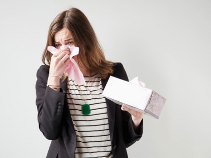 Studio shot of young woman sneezing. Photo : Jessica Peterson