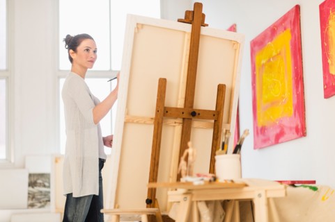 Woman painting at easel.