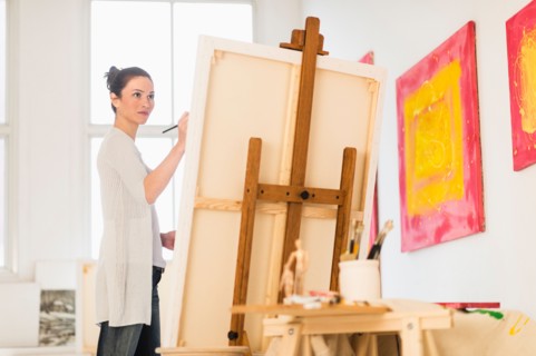 Woman painting at easel.