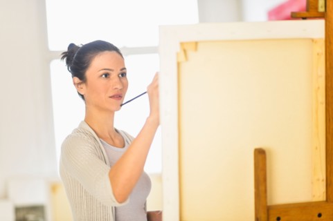 Woman painting at easel.