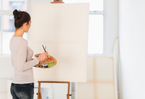 Woman painting at easel.