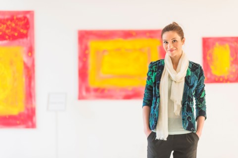 Portrait of woman with paintings in museum.