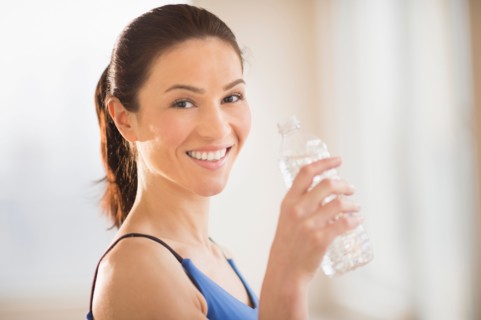 Portrait of woman drinking water in gym.