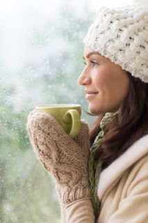 Woman in warm clothes holding mug.