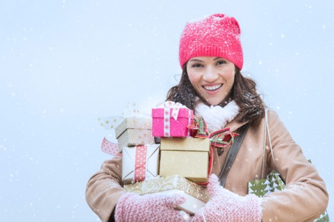 Portrait of woman in winter clothes carrying presents.