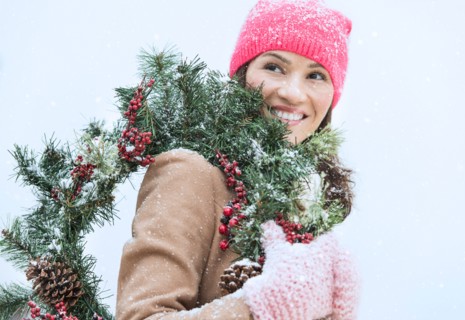 Portrait of woman in winter clothes carrying wreath.