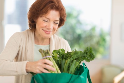 Senior woman with groceries in kitchen.