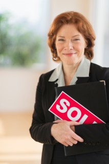 Portrait of female real estate agent holding sold sign.
