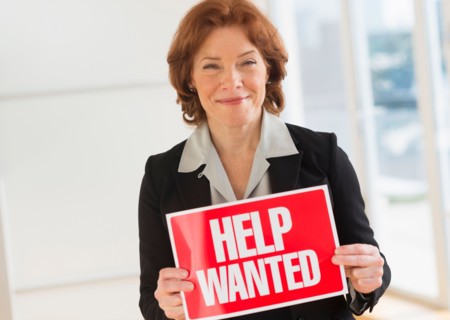 Portrait of businesswoman holding help wanted sign.