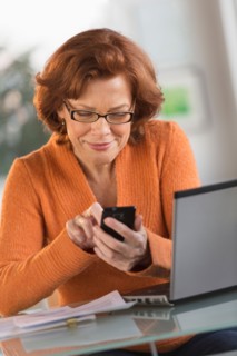 Senior woman working on laptop and text messaging.