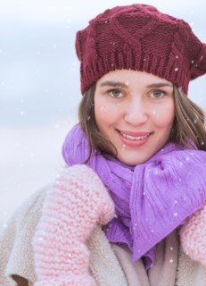 Portrait of young woman wearing knit hat, gloves and scarf.