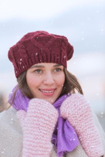 Portrait of young woman wearing knit hat, gloves and scarf.