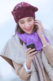 Young woman in wearing warm clothes and using mobile phone.