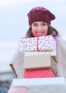 Portrait of young woman carrying stack of Christmas presents.