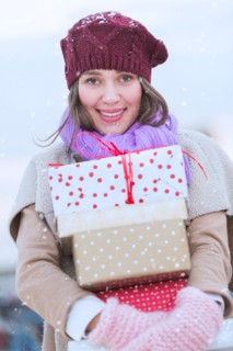 Portrait of young woman carrying stack of Christmas presents.