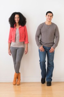Smiling couple standing against white wall.