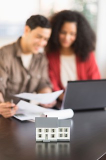 Smiling couple planning home ownership with model home.