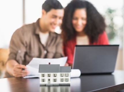 Smiling couple planning home ownership with model home.