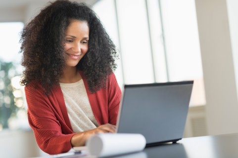 Smiling mid adult woman doing home finances with laptop.