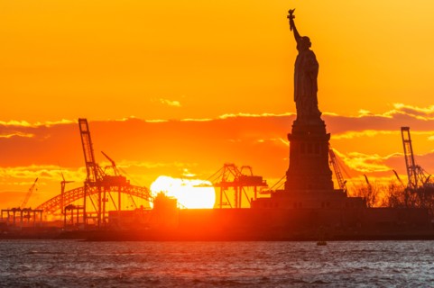 Silhouette of Statue of Liberty at sunset.