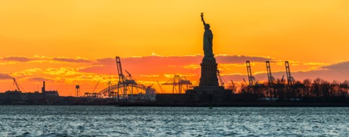 Silhouette of Statue of Liberty at sunset.