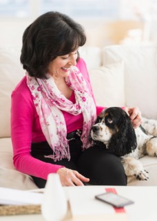 Portrait of senior woman sitting on sofa with her dog.
