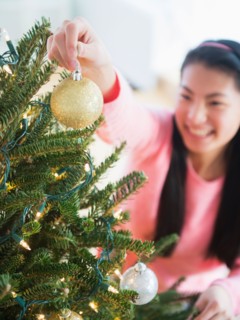 Teenage girl ( 16-17 years) decorating Christmas tree