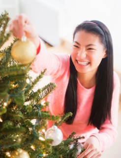 Teenage girl ( 16-17 years) decorating Christmas tree