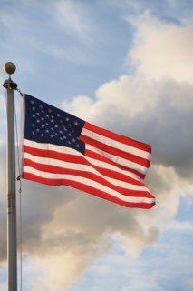 American flag in front of smoke stacks