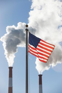 American flag in front of smoke stacks