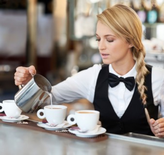 Female barista pouring milk into coffee cup