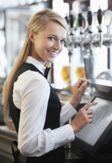 Young waitress using computer at restaurant counter