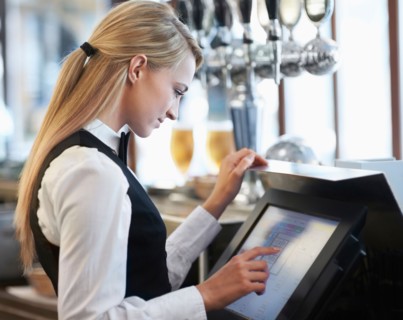 Young waitress using computer at restaurant counter