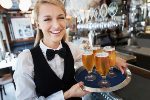 Portrait of young woman holding tray with beer glasses
