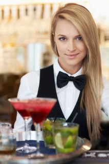 Portrait of female bartender holding tray with cocktails