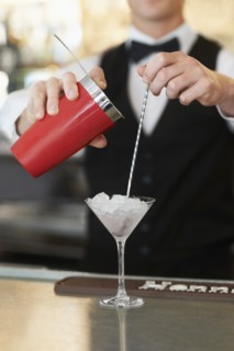 Young bartender pouring cocktail