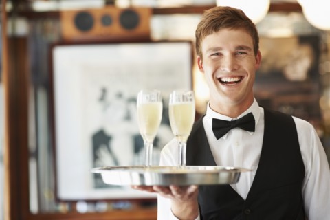 Portrait of waiter holding champagne flutes on tray