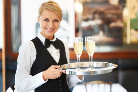 Portrait of waitress holding champagne flutes on tray