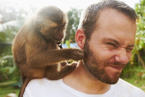 Portrait of adult man with macaque monkey sitting on his shoulder