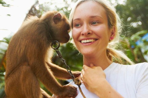 Portrait of young woman holding macaque monkey