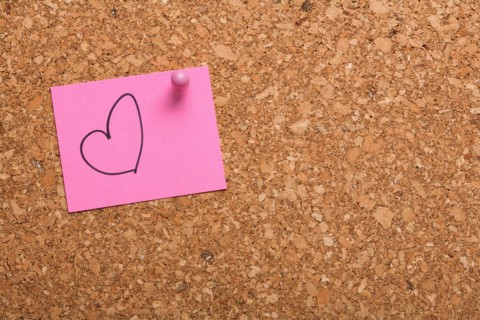 Note paper with drawn heart on corkboard