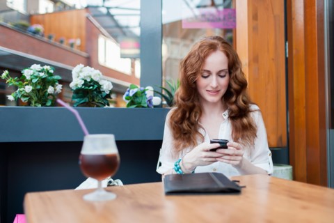 Elegant woman in cafe using mobile phone