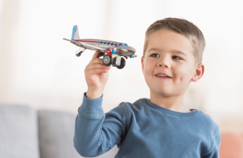Boy (4-5) playing with toy plane.