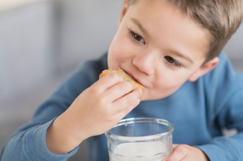 Boy (4-5) eating cookie.