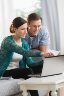 Couple using laptop together to pay bills.